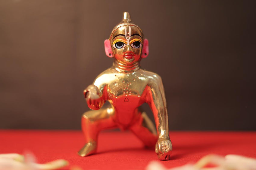 Laddu Gopal Ji brass murti, front view on a red cloth